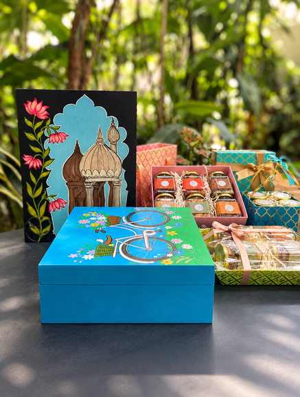 Hand-painted gift boxes and curated hampers arranged on a garden table
